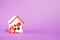 burning wooden model of a house, fire cut out of felt, purple background copy space,