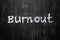 Burnout word handwritten on black wood background.