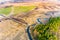 Burnt grass in field, aerial landscape. Narrow river flowing along small forest