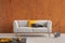 Burnt orange wabi sabi living room interior with grey couch with yellow and black pillows and newspaper rack