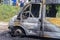 A burnt-out car on a city street, serious fire damage after a fire on the body of a passenger minibus