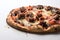 Burnt pizza dough with cheese, sausage and tomatoes in smoke on a white background.