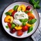 Burrata cheese salad with peaches, tomatoes, cranberries and basil on a dark gray background. Close up, top view. Healthy diet