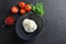 Burrata Italian cheese in black bowl with tomatoes basil on black surface space for text