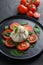 Burrata, Italian fresh cheese made from cream and milk of buffalo or cow.  on black plate over black stone surface top view close