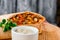 Burrito with vegetables, decorated with soy sprouts, served with cream sauce, on wooden plate on gray wooden background