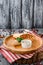 Burrito with vegetables, decorated with soy sprouts, served with cream sauce, on wooden plate on gray wooden background