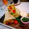 Burrito wraps with beef and vegetables on a wooden rectangular plate.  Beef burrito, Mexican food.