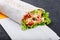 Burrito wraps from fillet grilled chicken, lettuce, slices of fresh tomatoes, pickles and cheese on dark wooden background