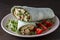 Burrito wraps with scrambled egg omelet and vegetables in green pita bread . Closeup