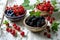 Bursting with freshness: A trio of bowls holds an assortment of vibrant berries on a white wooden surface