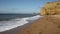 Burton Bradstock sandstone cliffs and waves crashing in to shore Dorset England uk