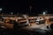 bus depot at night, with buses and other vehicles parked in the lot