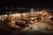 bus depot at night, with lit-up buses and other vehicles in view