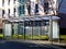 Bus shelter at a bus stop of glass and aluminum structure in public park setting