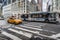 A bus and a yellow taxi on a New York Avenue.