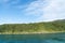 Bush-clad native bush covered hill catches bright sun along side of Queen Charlotte Sound in Marlborough Sounds of South Island