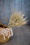 Bush of dry grass in basket decorated at cafe against wooden wall background.bundle of ears.Golden ears of wheat in vase