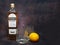 Bushmills whiskey bottle, branded whiskey glasses and lemon on dark vintage background, copy space