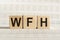 Business Acronym WFH as Work From Home on woode cubes. Concept