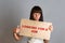 Business and advertising. A young brunette with a piercing holding a cardboard with text LOOKING FOR A JOB and points a finger at