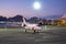 Business Airplane Parking Outside The Terminal In Airport. Private Jet Airliner, Luxury Corporate Aircraft, Airport Lights