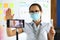 Business blogger in protective medical mask greets interlocutors via a smartphone.