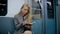 Business blond girl sitting in metro, writing in notebook, wearing headphones