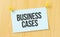 business cases sign written on sticky note pinned on wooden wall