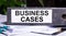 BUSINESS CASES is written on a gray file folder next to documents. Business concept