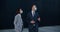 Business colleagues in business suits and protective masks stand near a modern building and talk about work topics