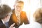 Business colleagues discussing while sitting at table during meeting in office lobby with yellow lens flare in background