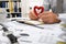 Business concept - businessman working in office and shows heart toy as love symbol, table and workspace close view, checks