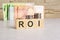 business concept. cubes with the inscription - ROI. euro and monet on grey table