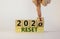 Business concept of new year 2021 reset. Businessman flips a wooden cube and changes words `reset 2020` to `reset 2021`. Beaut