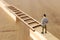 Business concept picture of challenge. A man stands on the edge of a high wall and passes the gap by placing a ladder. Problem