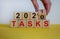 Business concept of planning 2021. Male hand flips wooden cube and change the inscription `Tasks 2020` to `Tasks 2021`. Beauti