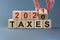 Business concept of planning 2021. Male hand flips wooden cube and change the inscription `Taxes 2020` to `Taxes 2021`. Beauti