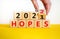 Business concept of planning 2022 hopes symbol. Businesman turns a wooden cube and changes words `Hopes 2021` to `Hopes 2022`.