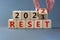 Business concept of planning 2022 reset symbol. Businesman turns a wooden cube and changes words `Reset 2021` to `Reset 2022`.