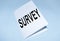 Business concept of a survey based on the method used to collect data  the word survey is written on white paper lying on a blue