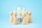 Business concept. Team concept and idea creation. Wooden figures of people stand around coins and a lamp on a blue background.