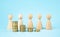 Business concept. Wooden figures of people stand around coins on a blue background. Teamwork. Earning money. Business ideas,