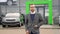 Business, confident stylish man stands with a bag near a car dealership before buying a new electric car