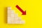 Business decrease concept abstract yellow background. Red arrow and wooden stairs