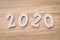 Business and design concept - wooden number 2020 for Happy new year text on wood table