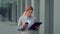 Business documentation. Concentrated businesswoman reading contract and typing message on smartphone at office building