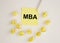 Business educatuion concept. paper sticker with text MBA acronym on yellow paper note with used papers around with white pen on