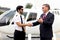 Business executives man in suits shaking hands with helicopter Commercial pilot in uniform near helicopter