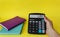 Business and finance concept.Female hand holding a calculator with the inscription - LIMIT on a yellow background. Near notebooks